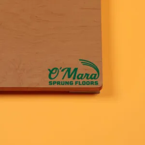 O'Mara Sprung Floors wooden panel against an orange background.