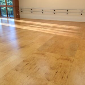 Wooden sprung dance floor in a sunlit studio with mirrors and ballet barres.