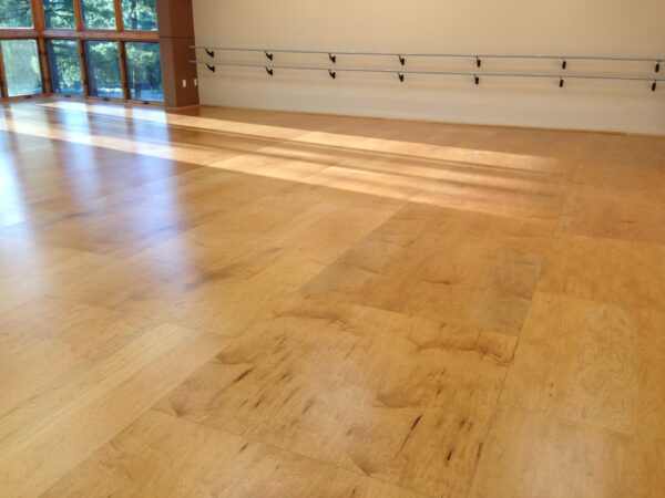 Wooden sprung dance floor in a sunlit studio with mirrors and ballet barres.