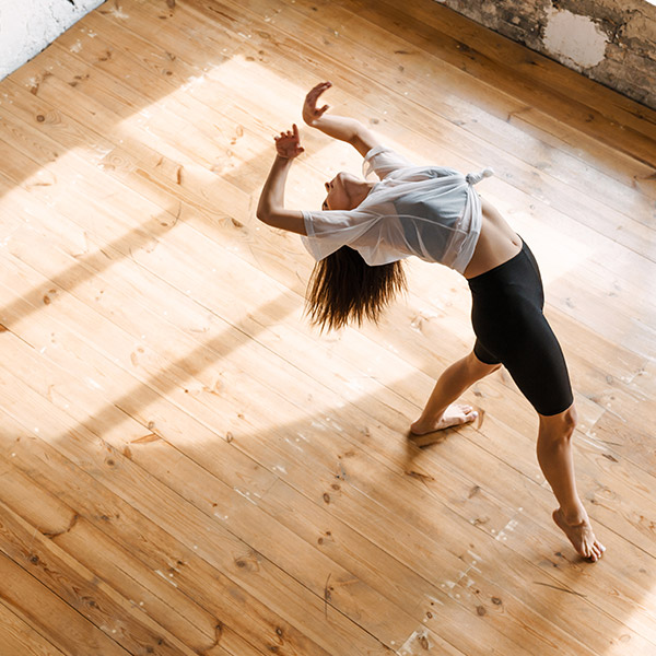Dancer performing on sprung wooden floor in natural light.