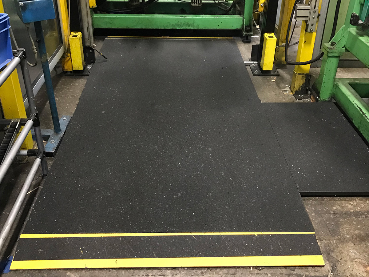 Durable black sprung floor panel with yellow trim installed in an industrial setting, suitable for heavy-duty use - SprungFloors.com