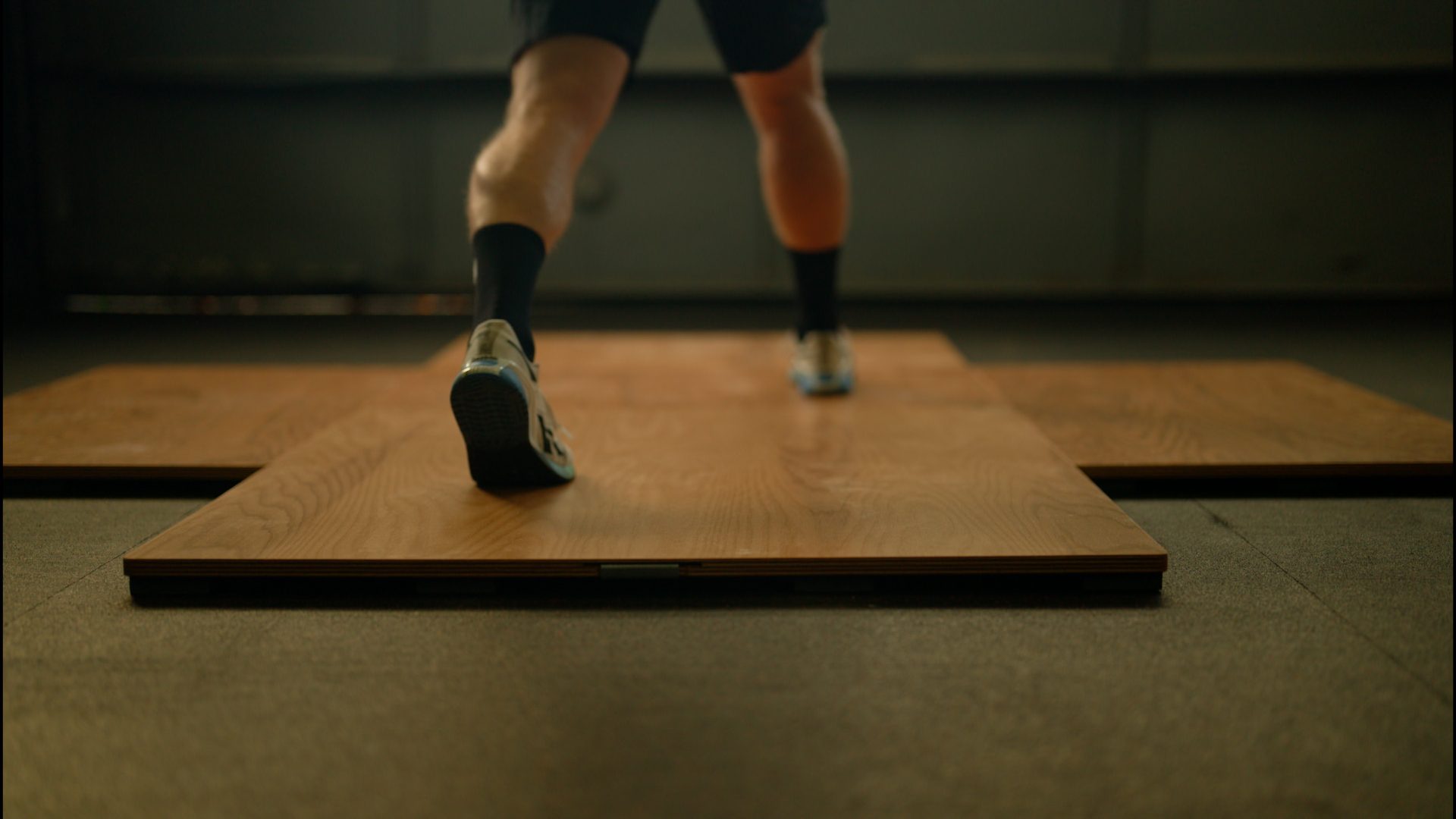 Person exercising on a sprung floor panel at a fitness facility.
