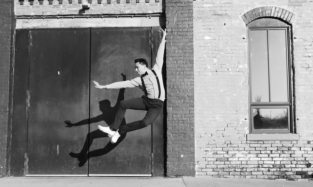 Dancer in motion captured mid-leap against urban backdrop, demonstrating flexibility and balance, perfect for high performance sprung floors available at sprungfloors.com