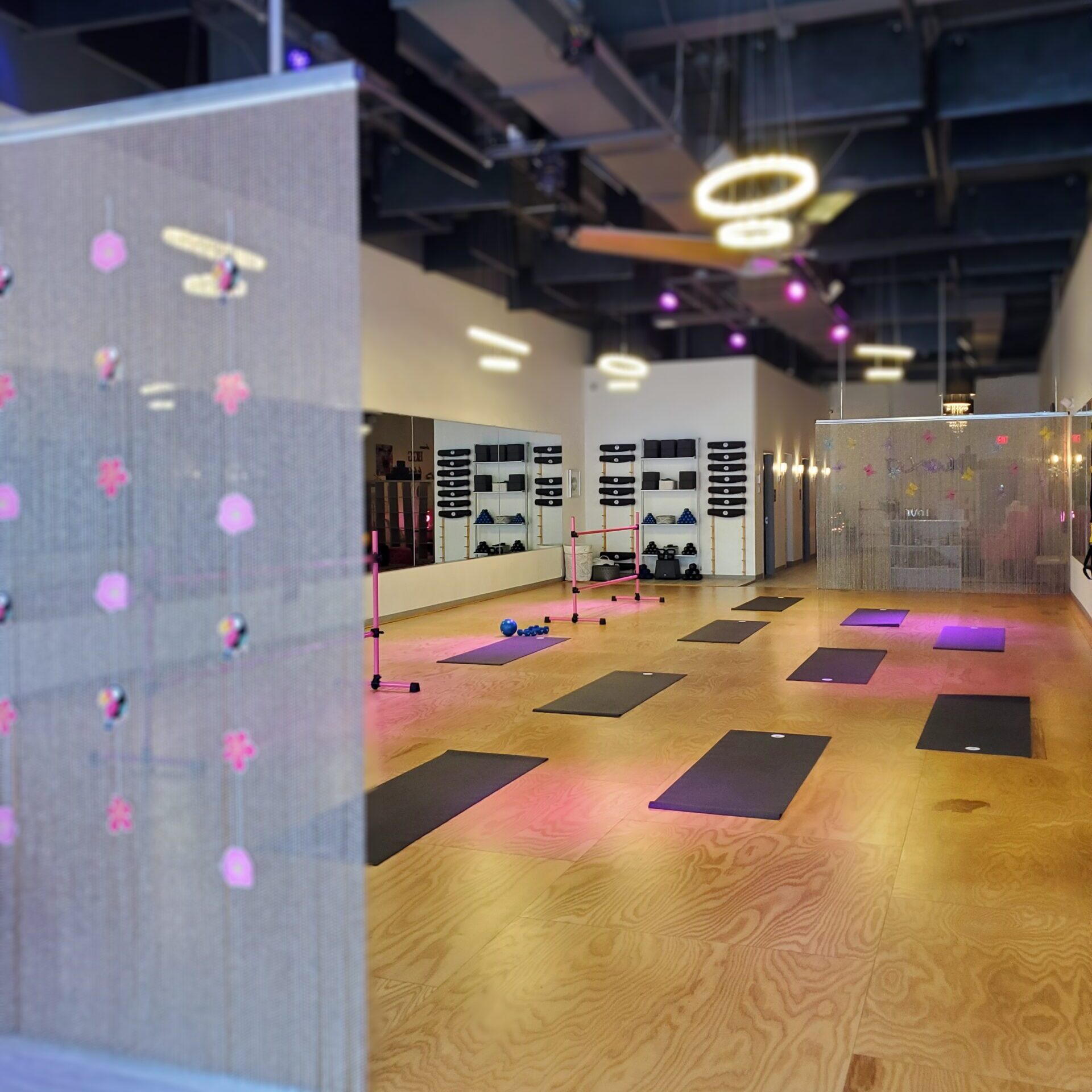 Modern dance studio featuring precision practice sprung floors, with yoga mats and ballet barres, under stylish lighting.